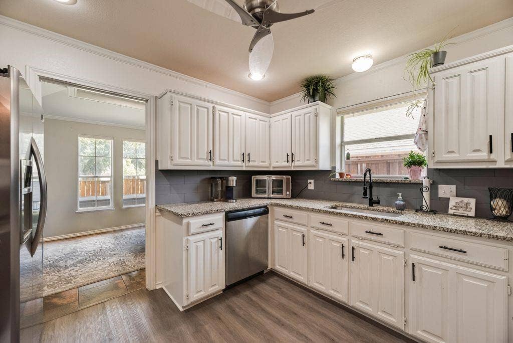 419 N Winding Oaks Drive, Wylie, TX 75098 Kitchen featuring white cabinetry, light granite countertops, a dark gray subway tile backsplash, stainless steel appliances, and wood-finish flooring