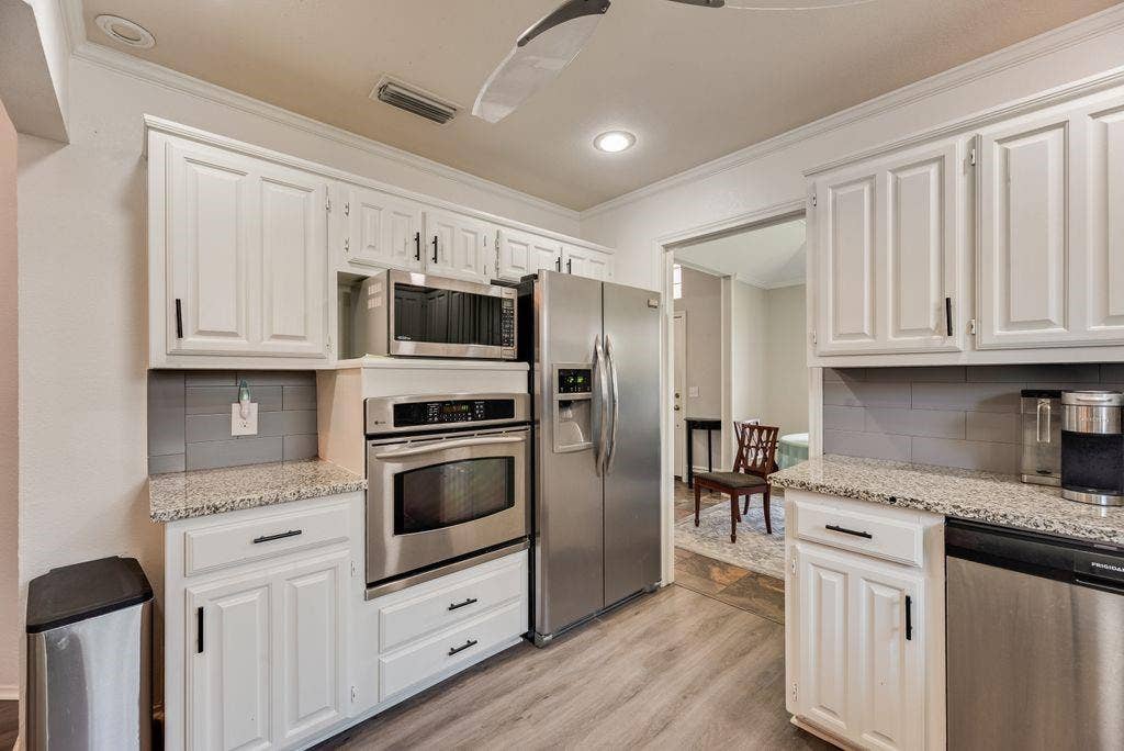 419 N Winding Oaks Drive, Wylie, TX 75098 Contemporary kitchen featuring white cabinetry, stainless steel appliances, granite countertops, a gray subway tile backsplash, and wood-finish flooring