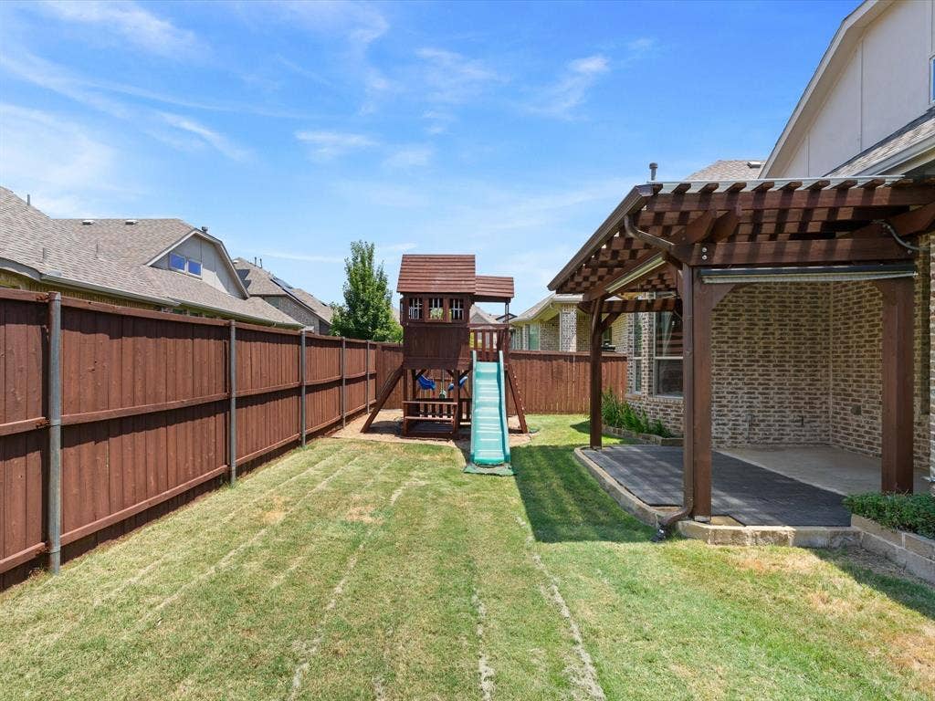 2703 Navarro Trail, Euless, TX 76039 Expansive fenced backyard featuring a covered patio with a wood pergola, brick exterior wall, and a separate play structure