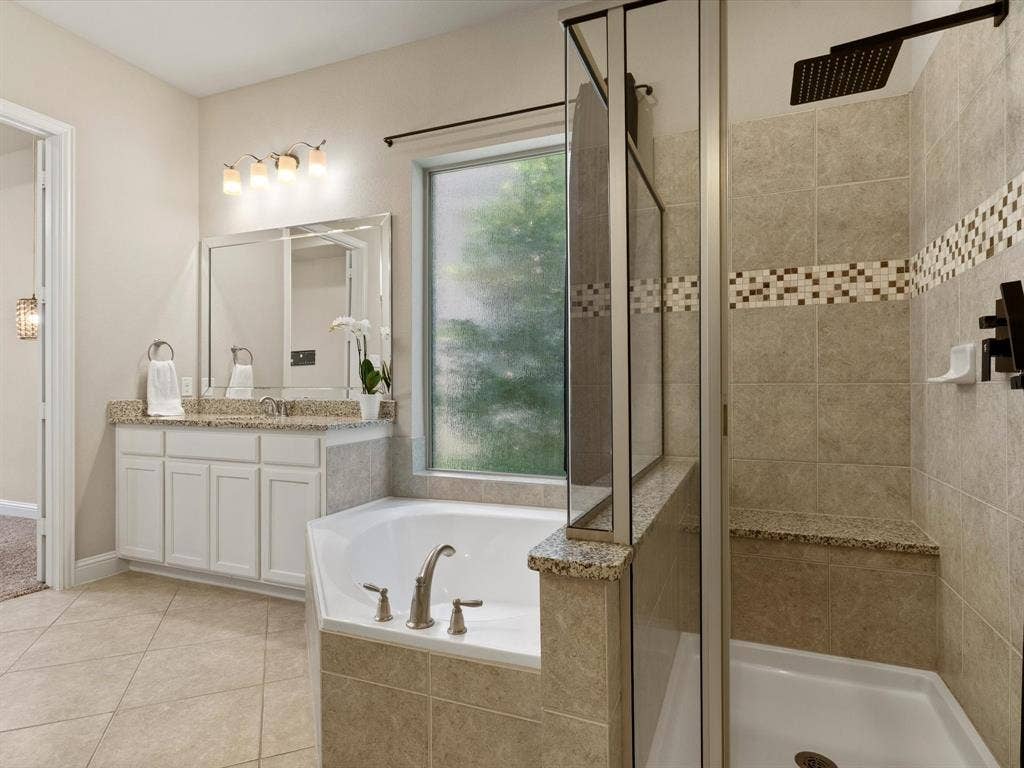 2703 Navarro Trail, Euless, TX 76039 Bathroom featuring a built-in soaking tub, separate glass-enclosed shower with rain showerhead, granite countertops, and tile flooring