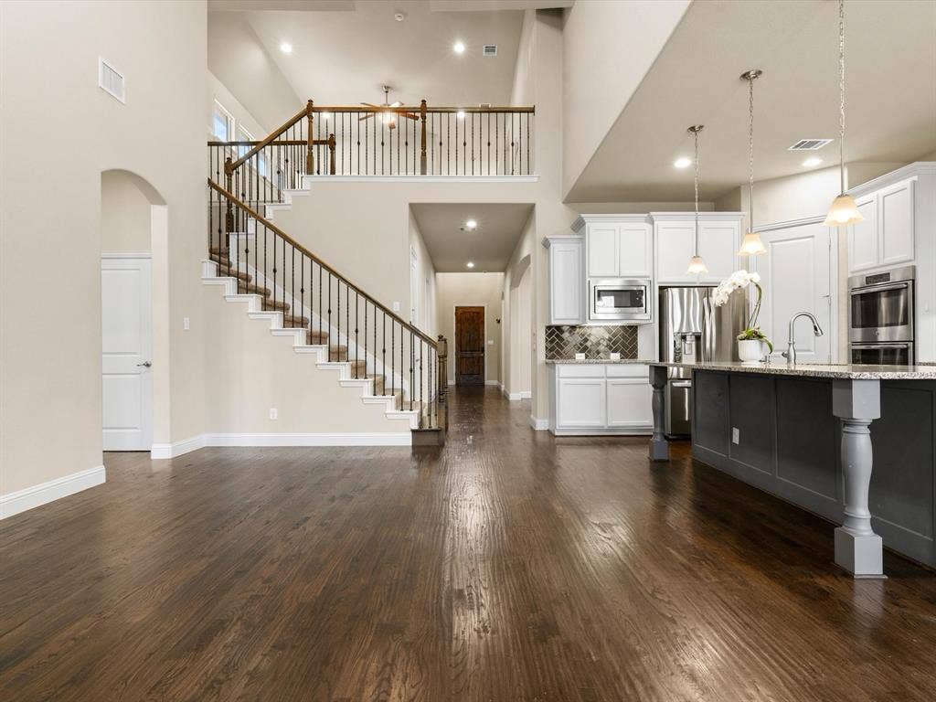 2703 Navarro Trail, Euless, TX 76039 Living/Kitchen and view of stair case with vaulted ceilings and wood-finished flooring