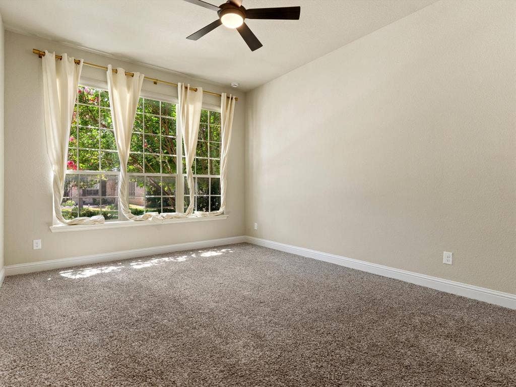 2703 Navarro Trail, Euless, TX 76039 Bright interior space featuring a large three-panel window with white trim, neutral textured walls, and a ceiling fan with dark blades, first floor