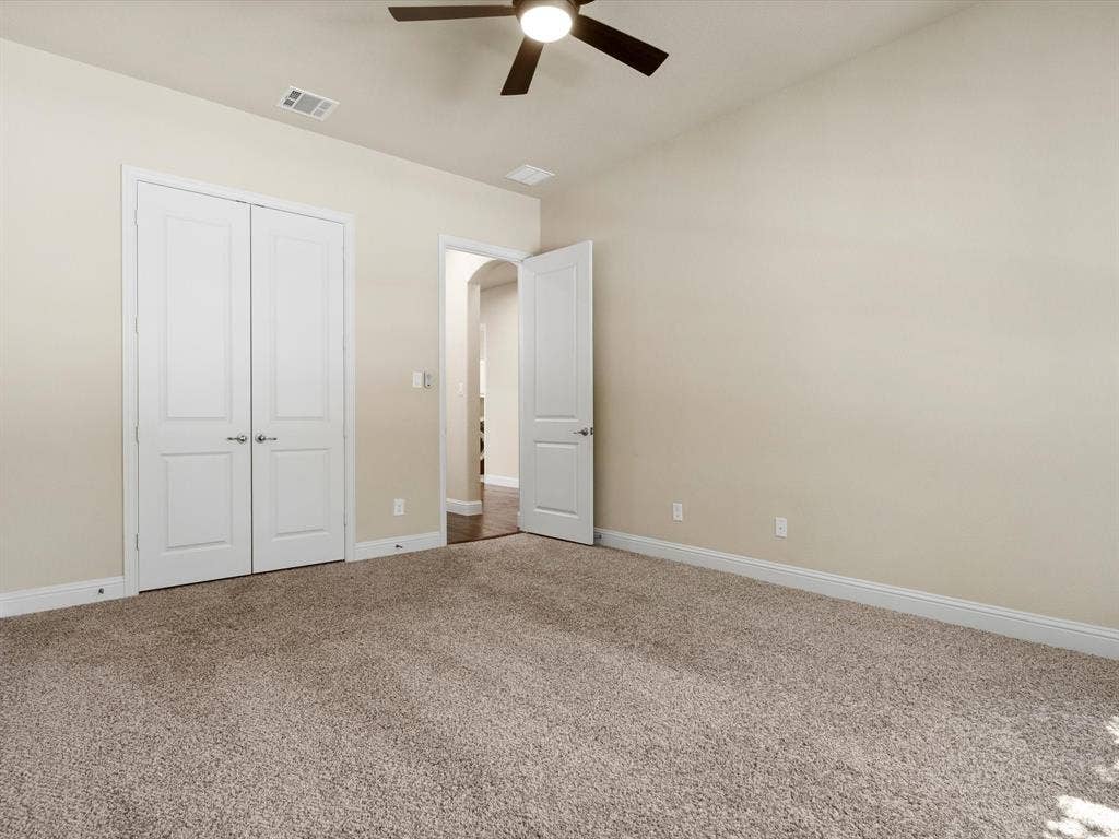 2703 Navarro Trail, Euless, TX 76039 Spacious room featuring neutral carpeting, light-toned walls, white baseboards, a ceiling fan with integrated lighting, and a white double-door closet, second floor