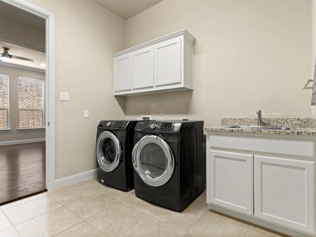 2703 Navarro Trail, Euless, TX 76039 Laundry room featuring tile flooring, white shaker cabinetry, a built-in sink with a granite-finish countertop, and overhead storage