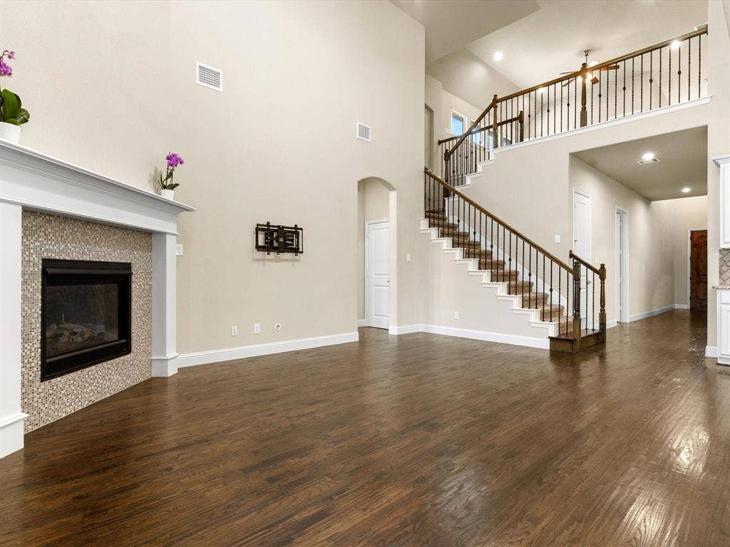 2703 Navarro Trail, Euless, TX 76039 Expansive living space featuring high ceilings, wood-finish flooring, and a fireplace with a mosaic tile surround