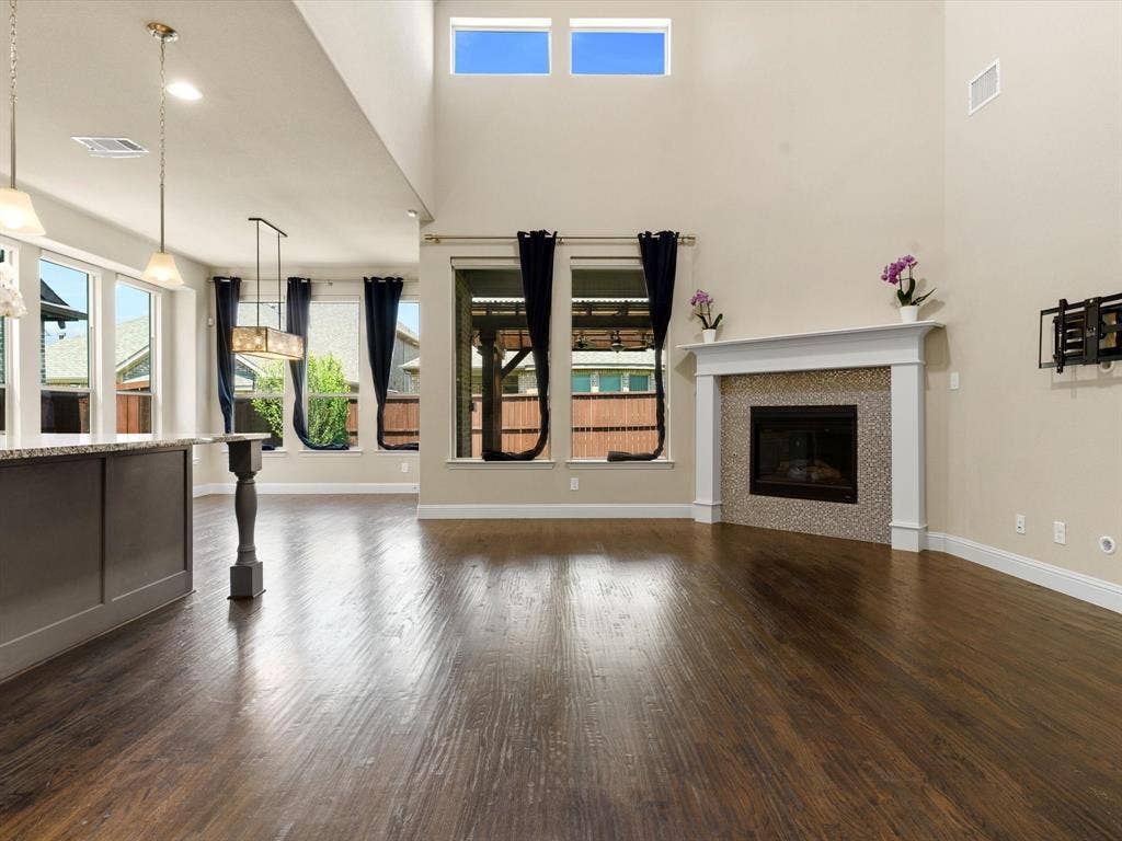 2703 Navarro Trail, Euless, TX 76039 Living area featuring wood-finish flooring, a fireplace with a tiled surround and white mantel, and high ceilings