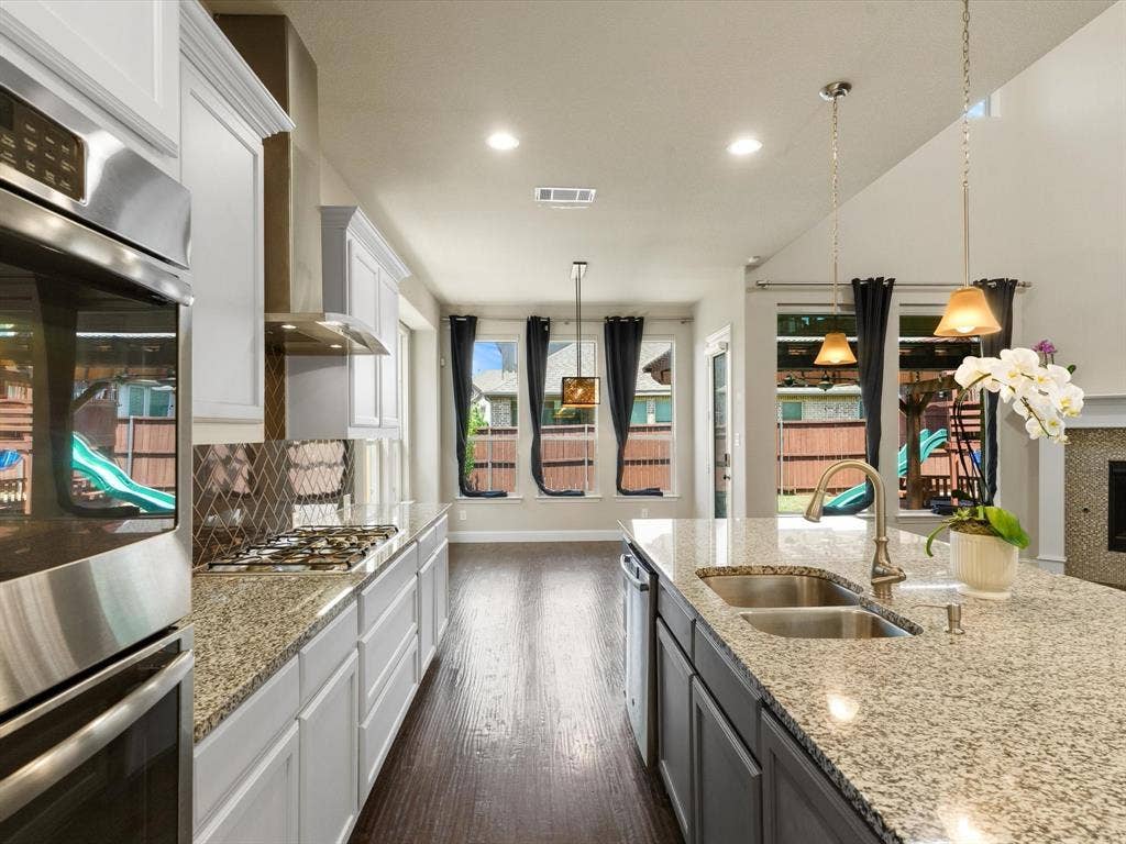 2703 Navarro Trail, Euless, TX 76039 Gourmet kitchen featuring a built-in stainless steel double oven, gas cooktop, microwave, dishwasher, white shaker cabinetry, and light granite countertops