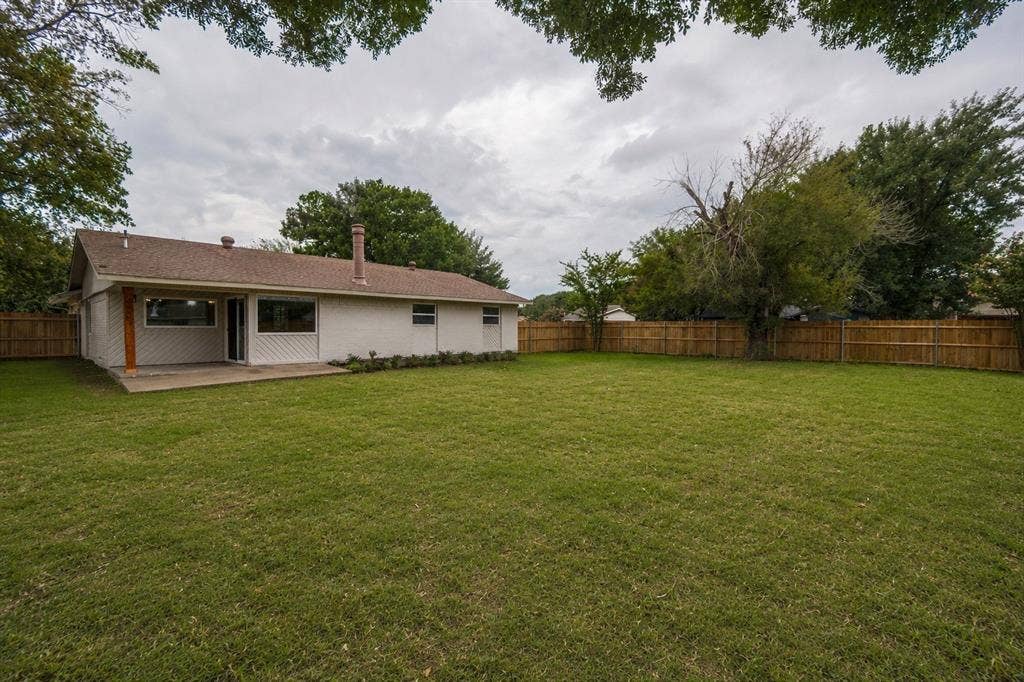 641 Stroud Lane, Garland, TX 75043 Expansive grassy lawn with a wood privacy fence