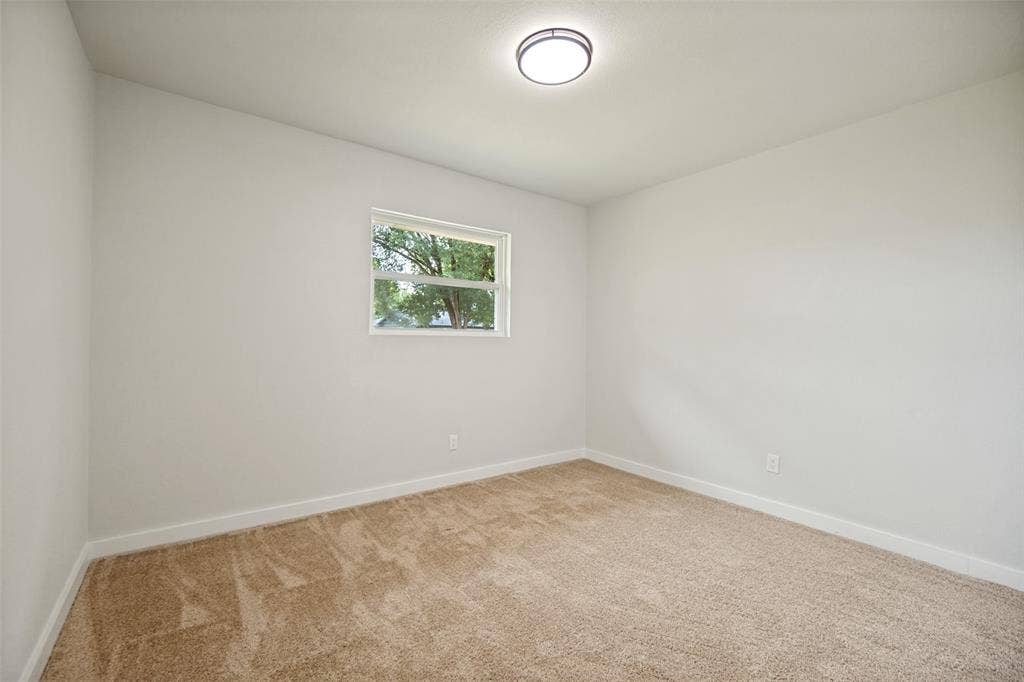 641 Stroud Lane, Garland, TX 75043 Bright room featuring neutral-toned carpet, a double-hung window, and a flush-mount ceiling light fixture