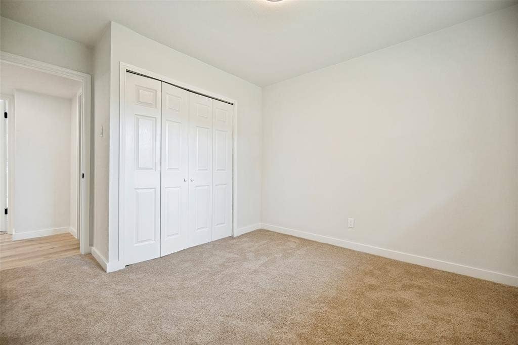 641 Stroud Lane, Garland, TX 75043 Carpeted room featuring a four-panel bi-fold closet, white walls, and white baseboards