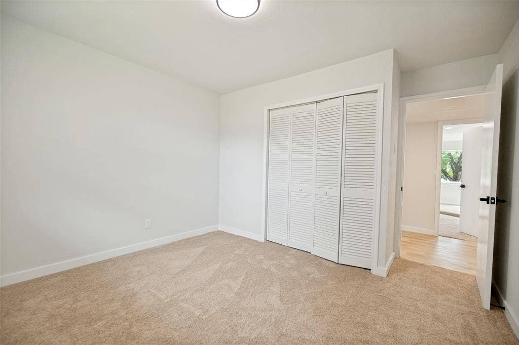 641 Stroud Lane, Garland, TX 75043 Spacious room featuring neutral carpeting, white baseboards, and a white interior door with black hardware