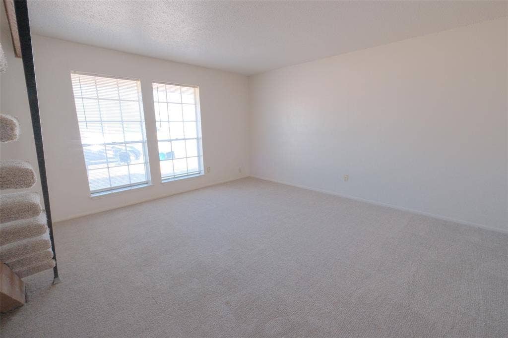 6317 Granbury Road, #6321, Fort Worth, TX 76133 Spacious room featuring neutral carpeting, light-toned walls, and two large windows with horizontal blinds