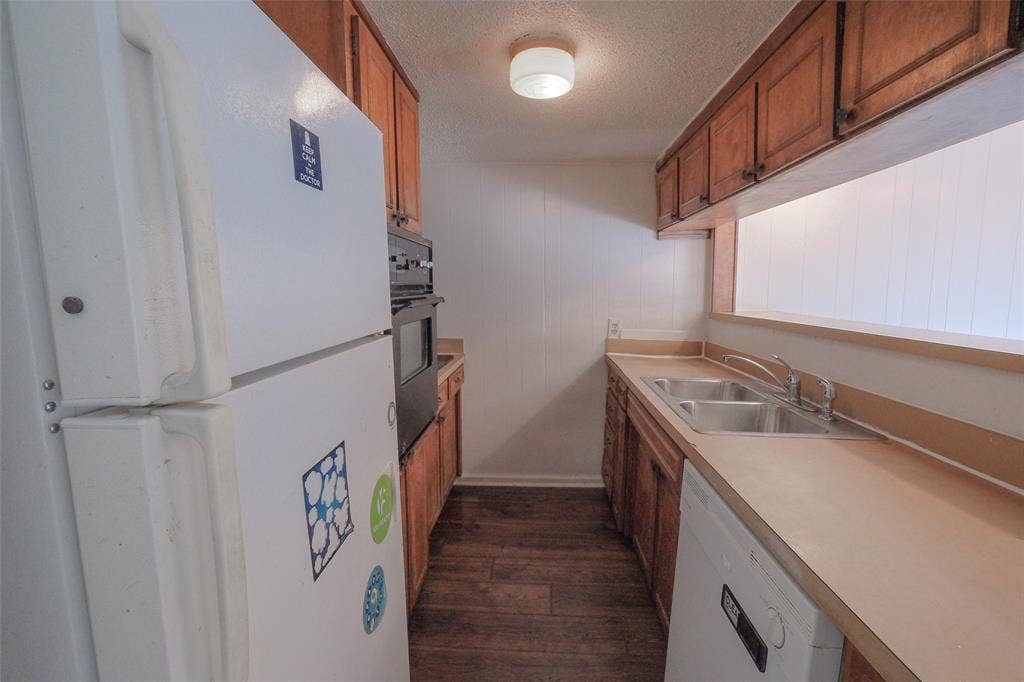 6317 Granbury Road, #6321, Fort Worth, TX 76133 Kitchen featuring wood-finish flooring, wood cabinetry, a dual-basin stainless steel sink, and a built-in oven