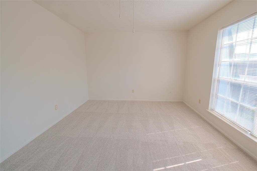 6317 Granbury Road, #6321, Fort Worth, TX 76133 Neutral-toned room featuring a large window with horizontal blinds, light-colored carpet, and a ceiling fan