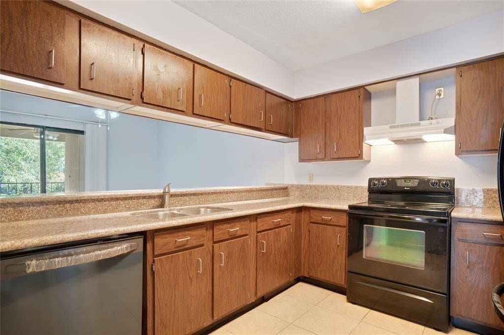 8100 Cambridge Street, #124, Houston, TX 77054 Kitchen featuring wood cabinetry, stone-look countertops, a double basin sink, black range, and black dishwasher
