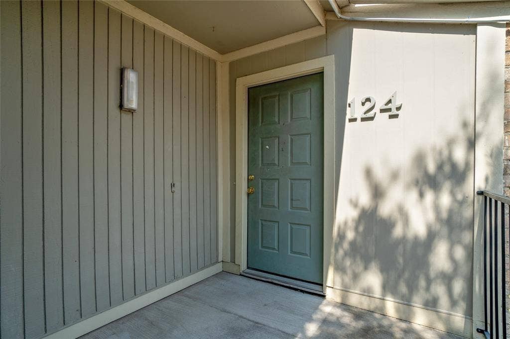 8100 Cambridge Street, #124, Houston, TX 77054 Entryway featuring a paneled door, vertical siding, and exterior lighting