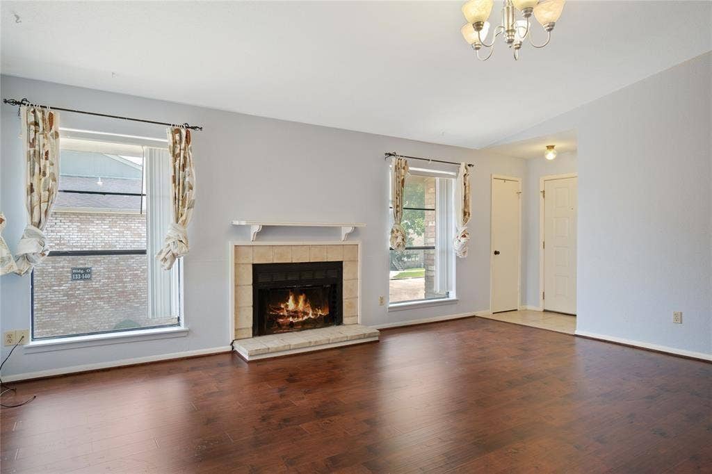 8100 Cambridge Street, #124, Houston, TX 77054 Living area featuring wood-finish flooring, a tile-surround fireplace with a white mantel, and multiple windows
