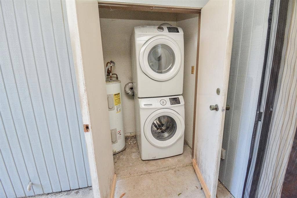 8100 Cambridge Street, #124, Houston, TX 77054 Utility closet featuring a stacked washer and dryer unit, a water heater, and light-colored louvered door