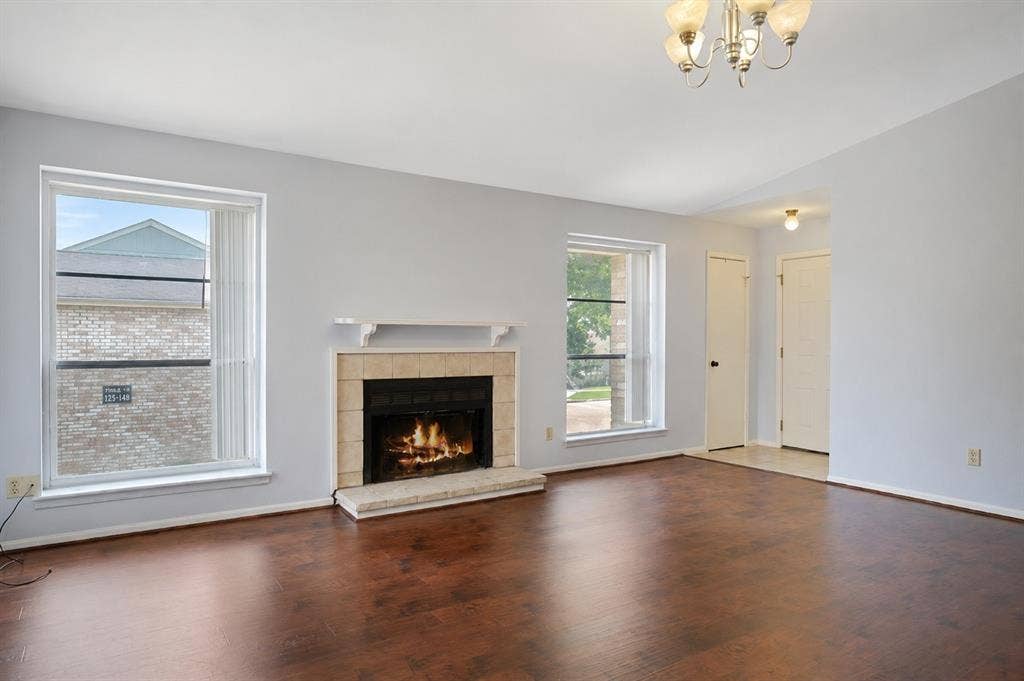 8100 Cambridge Street, #124, Houston, TX 77054 Living area featuring wood-finish flooring, a tiled fireplace with a mantel, and two large windows