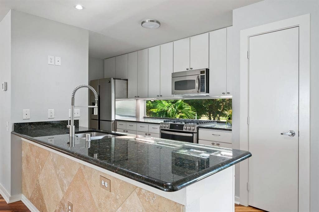 Kitchen island with a black stone countertop and undermount sink, complemented by a pull-down faucet