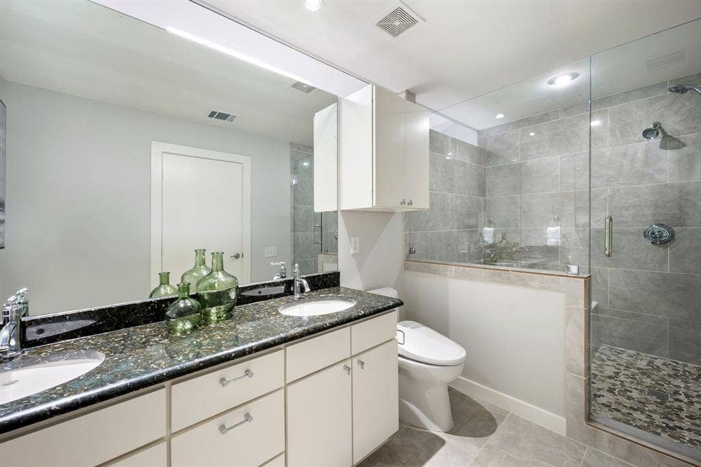 Dual vanity with undermount sinks, speckled dark countertop, and chrome fixtures