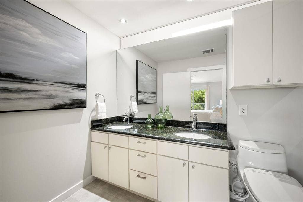 Dual basin vanity with a speckled countertop, integrated sinks, and polished chrome fixtures