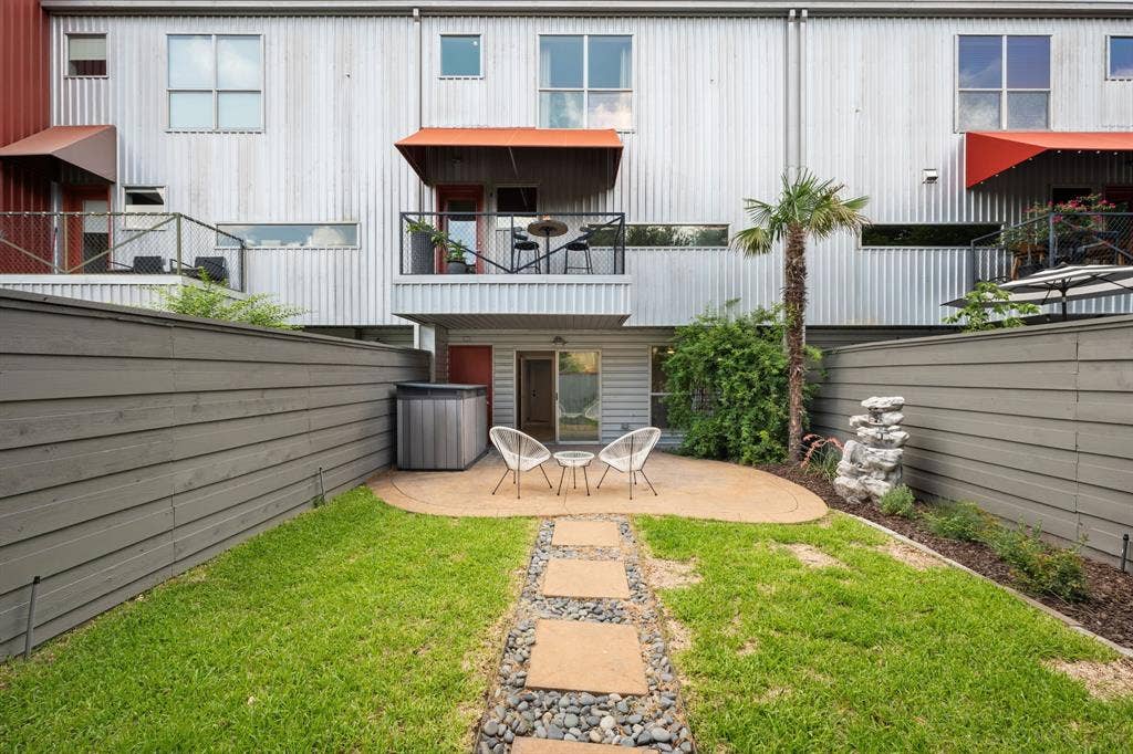 Fenced backyard featuring a manicured lawn, stone paver pathway, and a curved concrete patio