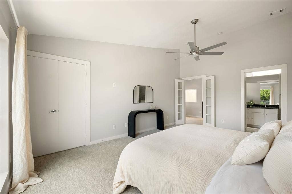 Vaulted ceiling featuring a ceiling fan, carpet flooring, double closet doors, and French doors leading to an additional space