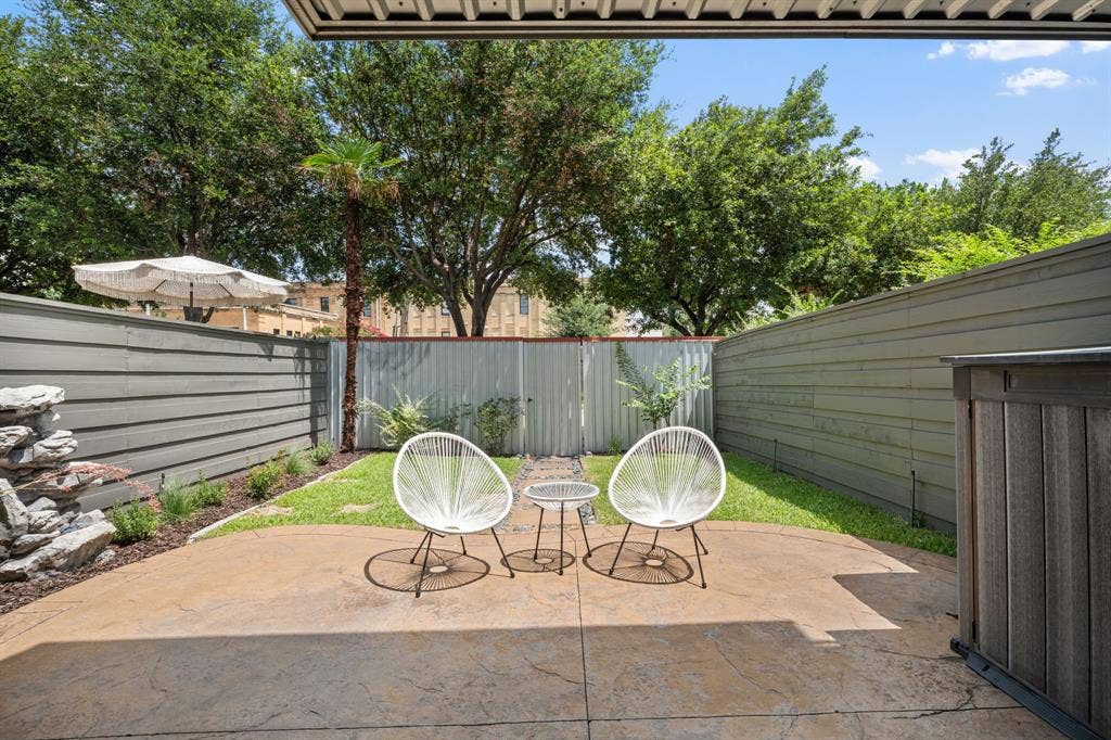 Private outdoor patio featuring a stamped concrete surface, manicured lawn, and a stacked stone water feature