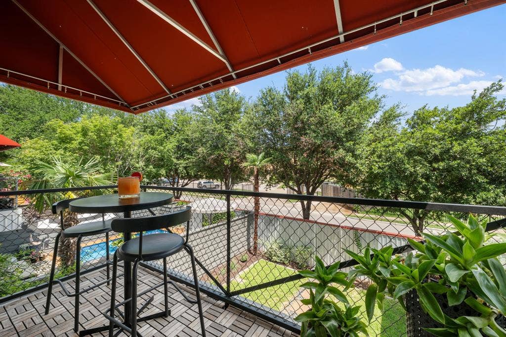 Outdoor patio with a red retractable awning and wood-finish tile flooring
