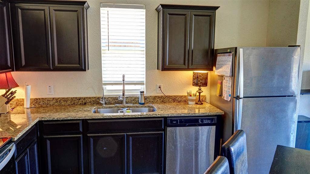 741 Windsor Court, Lavon, TX 75166 Dark wood-finish cabinetry, light-toned countertops, stainless steel appliances, and a double-basin sink with a chrome faucet