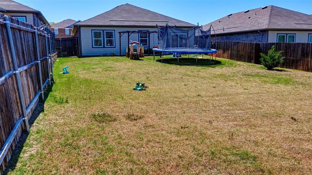 741 Windsor Court, Lavon, TX 75166 Expansive backyard featuring a privacy fence and a rear exterior with a sliding glass door