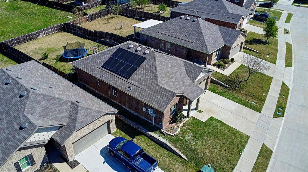 741 Windsor Court, Lavon, TX 75166 Brick exterior with an attached garage, featuring solar panels on the roof and a fenced backyard