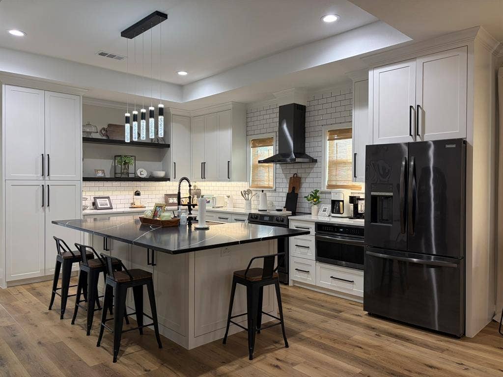 600 Lucas Drive, Athens, TX 75751 Spacious kitchen featuring an expansive center island with seating, dark stone-finish countertops, subway tile backsplash, light-toned cabinetry, and wood-finish flooring