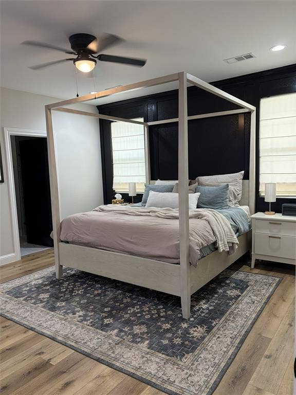 600 Lucas Drive, Athens, TX 75751 Bedroom featuring wood-finish flooring, a contemporary ceiling fan with integrated lighting, and dark accent paneling