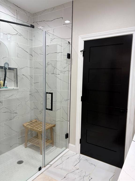 600 Lucas Drive, Athens, TX 75751 Modern bathroom featuring a frameless glass shower enclosure with matte black hardware, white subway tile with dark veining, and a black paneled door with matte black hardware