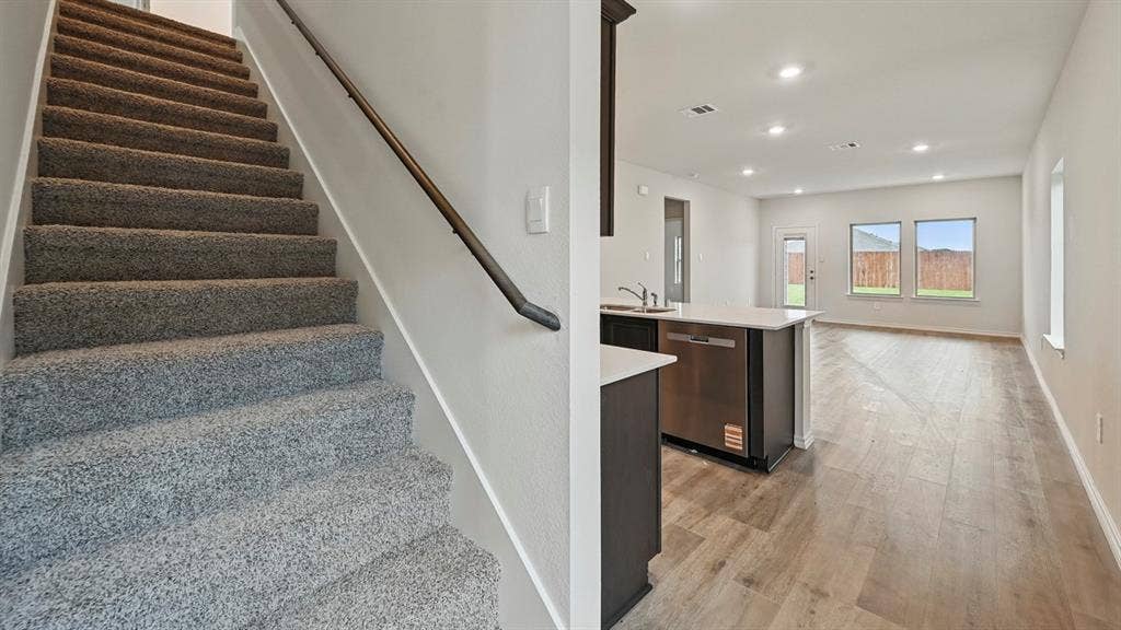 5602 Gannet Place, Crandall, TX 75114 Open-concept living space featuring wood-finish flooring, recessed lighting, and an island kitchen with a stainless steel dishwasher