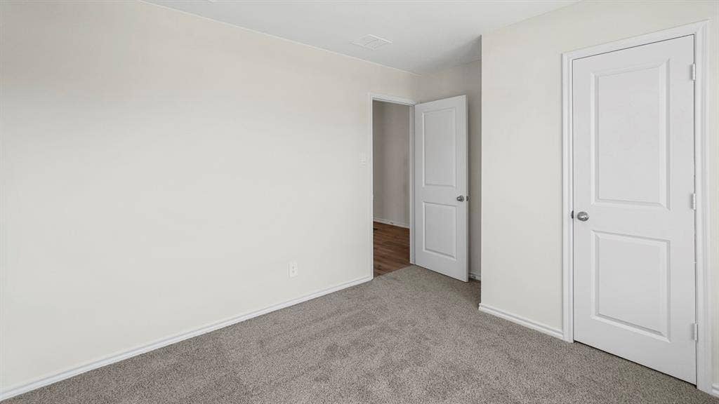 2912 Peppergrass Street, Royse City, TX 75189 Neutral-toned room featuring gray carpeting, white baseboards, and two white two-panel doors with brushed nickel hardware