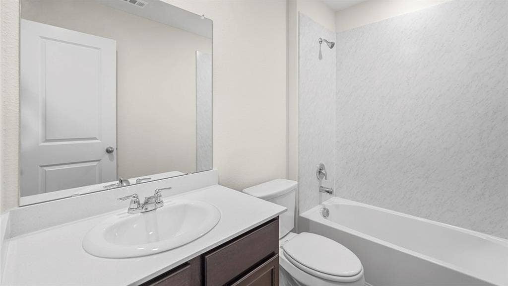 2912 Peppergrass Street, Royse City, TX 75189 Bathroom featuring a white bathtub with a shower, a dark wood-finish vanity with a light countertop, an undermount sink, and a large wall-mounted mirror