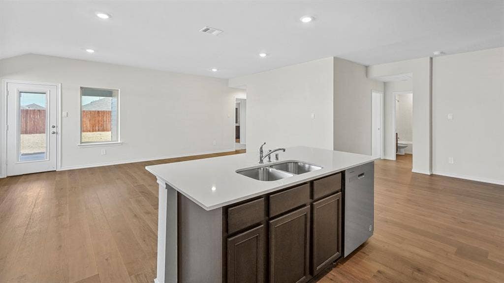2912 Peppergrass Street, Royse City, TX 75189 Kitchen island featuring a double-basin stainless steel sink with a high-arc faucet, integrated dishwasher, and white countertop
