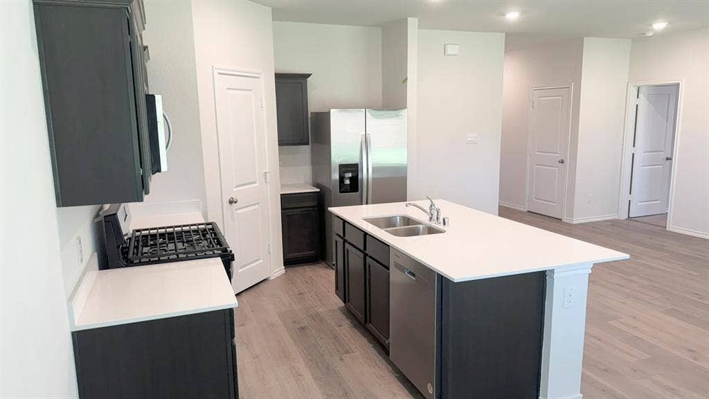 5004 Shumard Drive, Lindale, TX 75771 Modern kitchen featuring dark cabinetry, white countertops, stainless steel appliances, and wood-finish flooring