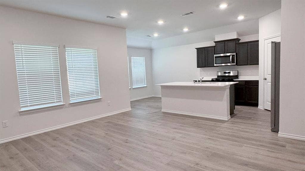 5004 Shumard Drive, Lindale, TX 75771 Open-concept kitchen and living area featuring wood-finish flooring, recessed lighting, and a kitchen island with a double sink