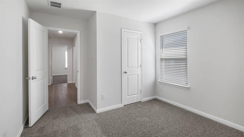 151 Arion Road, Waxahachie, TX 75165 Carpeted room featuring a single window with blinds, white trim, and a white six-panel door