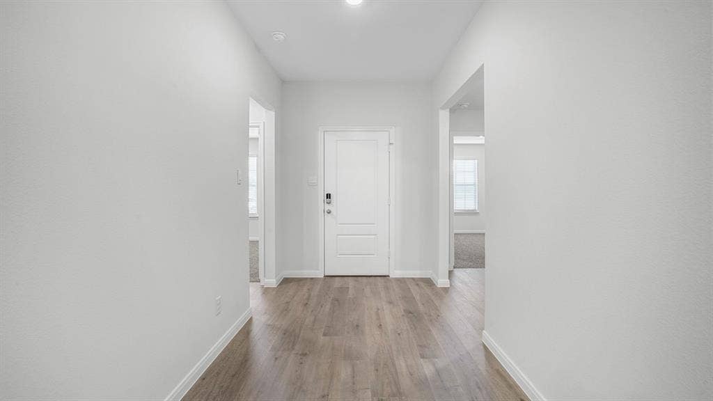 151 Arion Road, Waxahachie, TX 75165 Bright entryway featuring wood-finish flooring, white trim, and a white paneled door with modern hardware