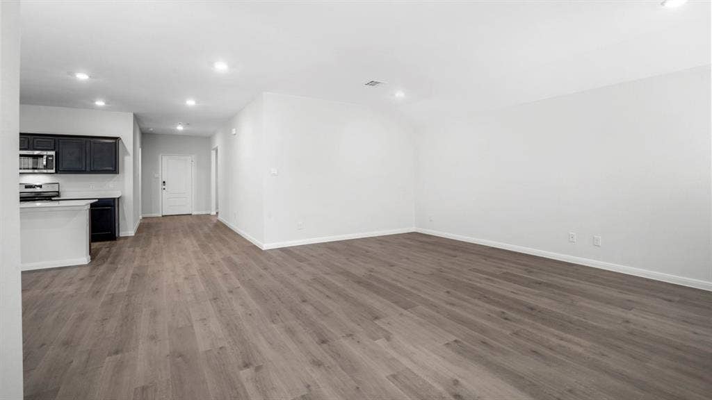 151 Arion Road, Waxahachie, TX 75165 Open-concept living space featuring wood-finish flooring, recessed lighting, and a kitchen with dark cabinetry, light countertops, and stainless steel appliances
