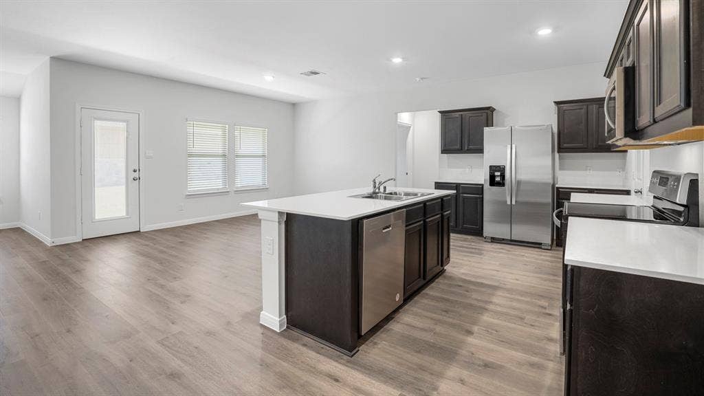 151 Arion Road, Waxahachie, TX 75165 Modern kitchen featuring dark wood cabinetry, white countertops, stainless steel appliances, and wood-finish flooring