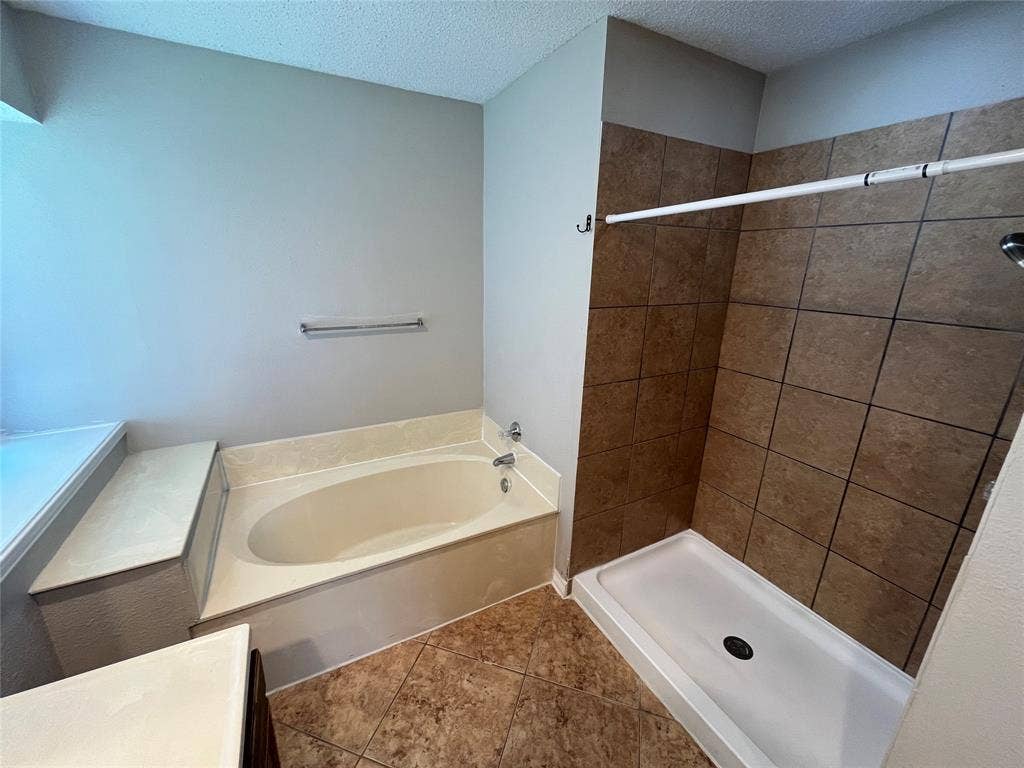 2405 Brookside Drive, Rowlett, TX 75088 Built-in soaking tub with a tiled surround, separate shower with tiled walls, and coordinating floor tiling