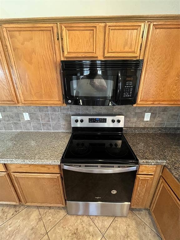 2405 Brookside Drive, Rowlett, TX 75088 Stainless steel and black range, coordinating over-the-range microwave, granite-look countertops, subway tile backsplash, and light wood-finish cabinetry