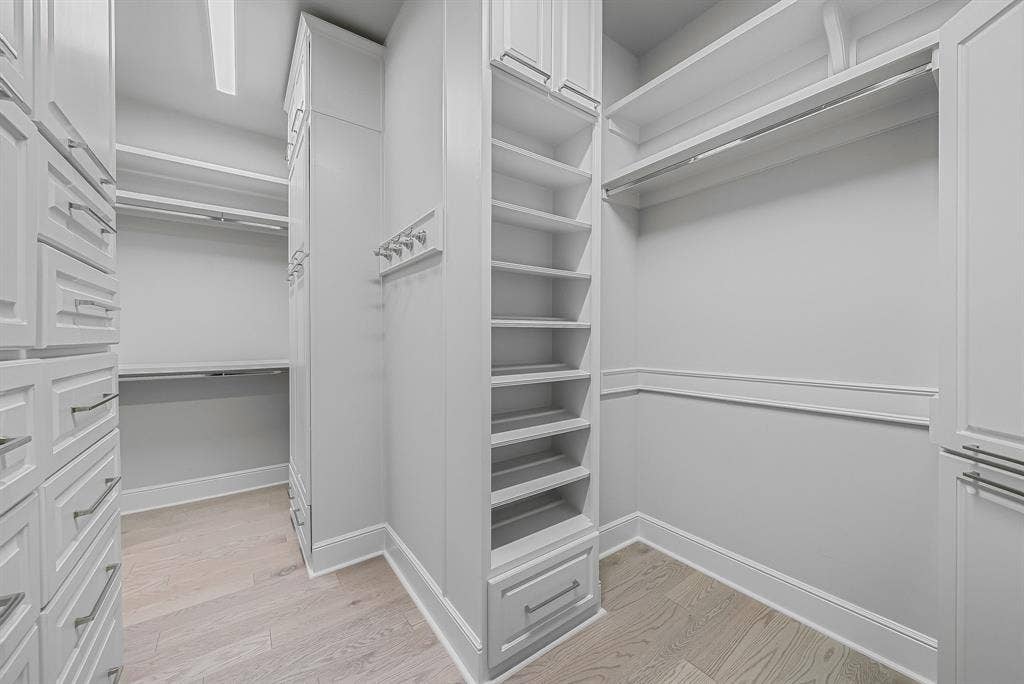 4240 Prescott Avenue, #8B, Dallas, TX 75219 Custom built-in closet system featuring extensive shelving, hanging rods, drawer storage, and light wood-finish flooring