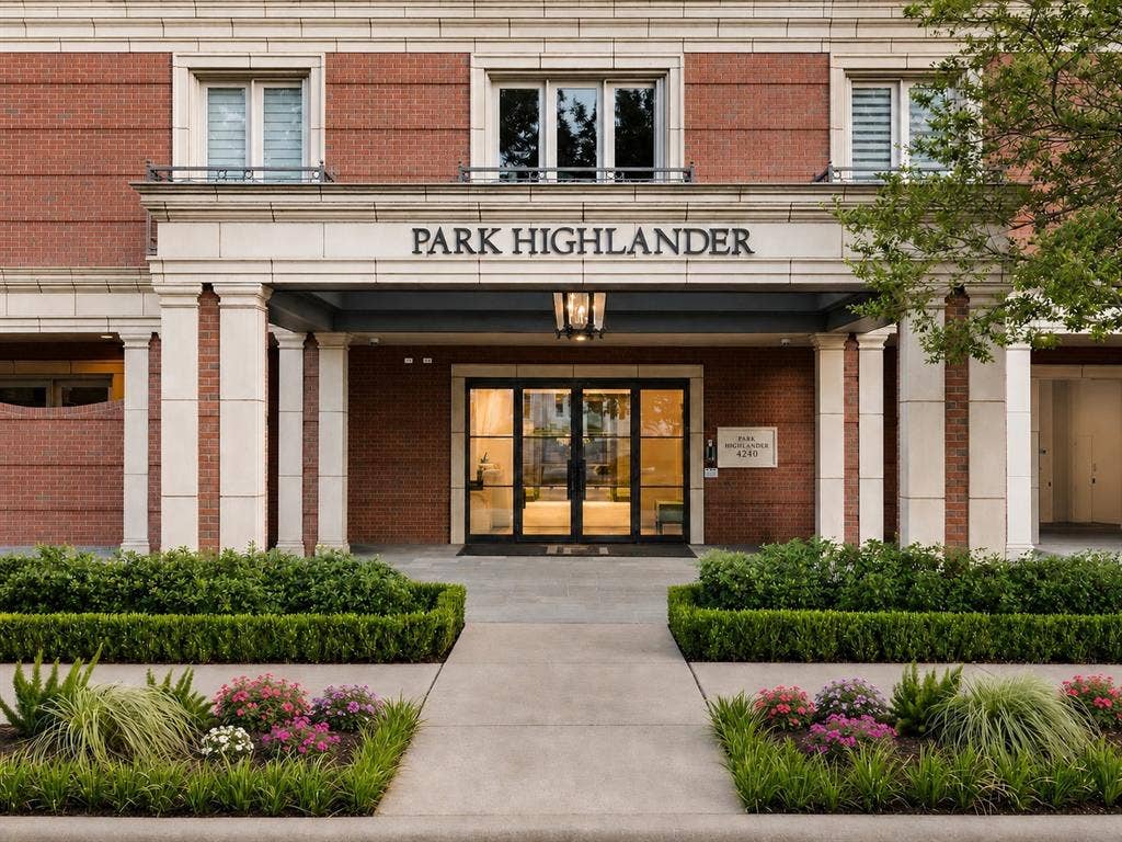 4240 Prescott Avenue, #8B, Dallas, TX 75219 Brick facade with stone detailing, prominent entryway with columns, glass double doors, professional landscaping, and an overhead exterior light fixture